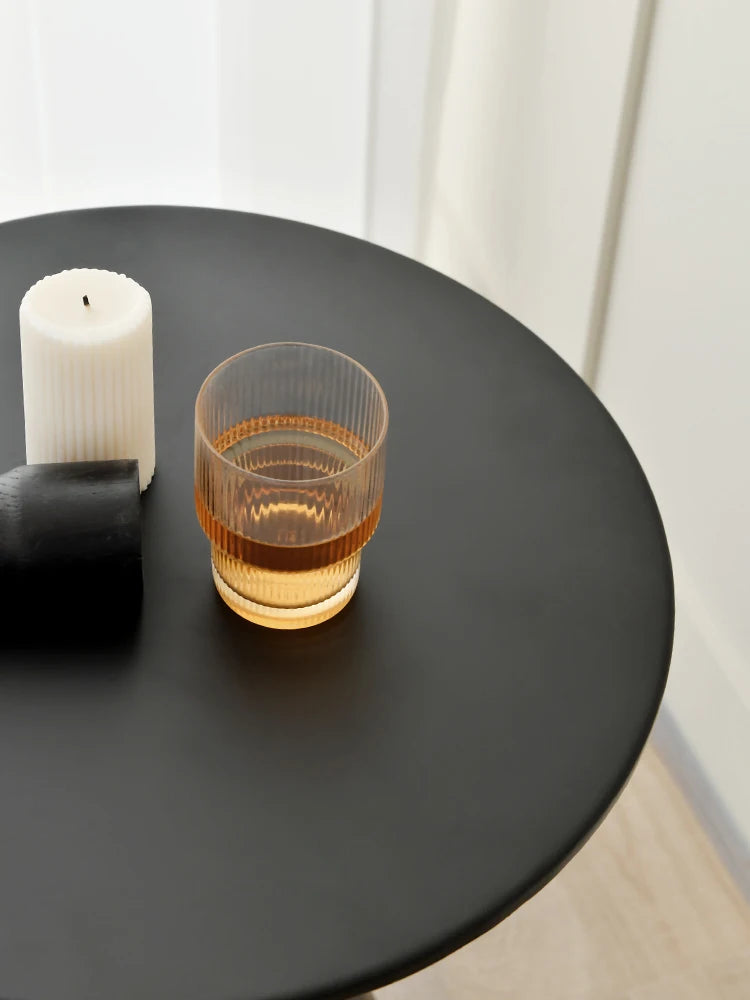 Detail of round top of sleek black lightweight metal side table in minimalist living room