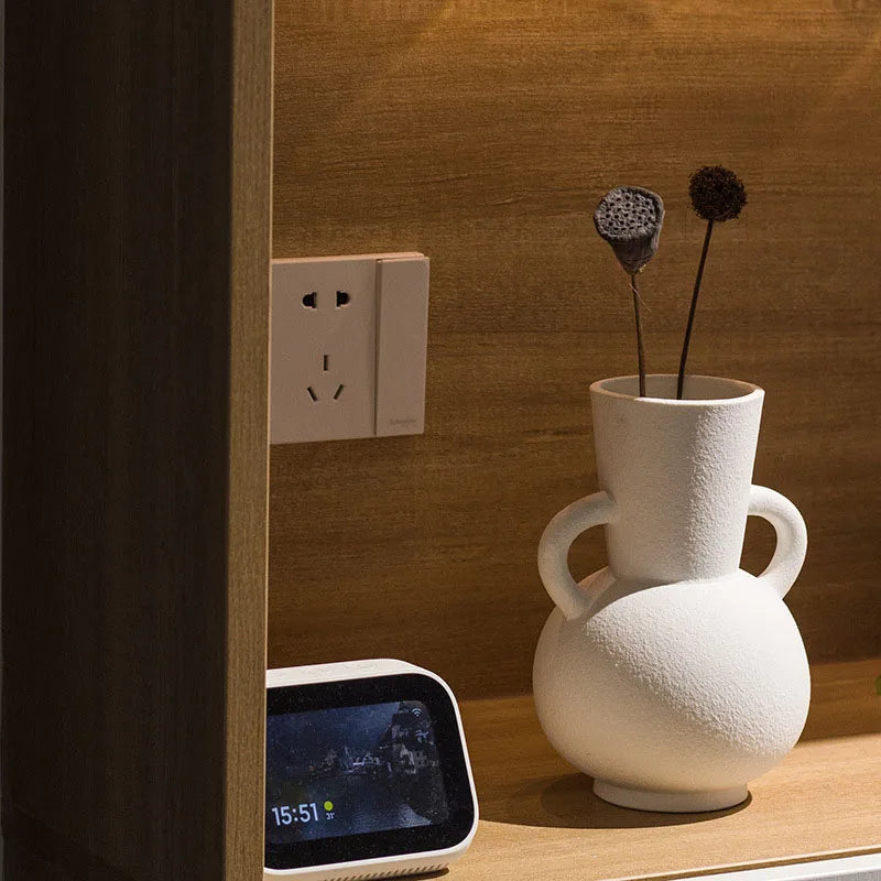 White textured vase with two handles, on wooden shelf