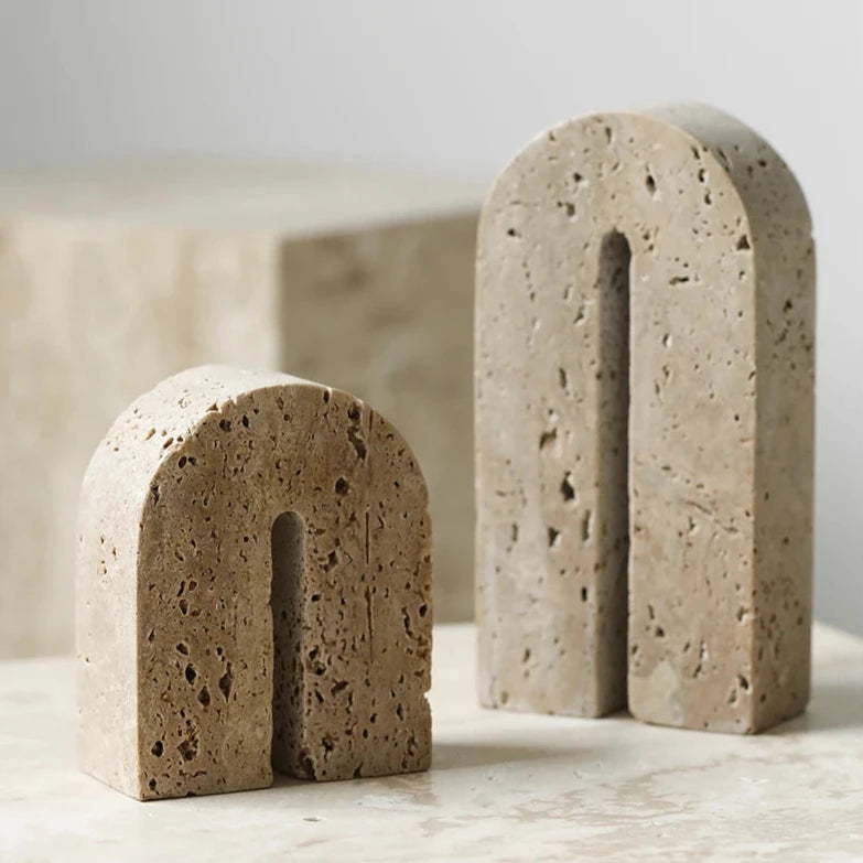 Set of handcrafted, arch shaped travertine book ends on neutral background
