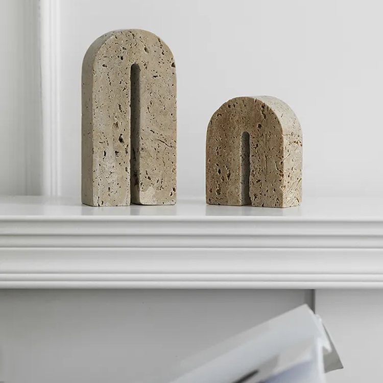 A set of two handcrafted, arch shaped travertine book ends on white mantle