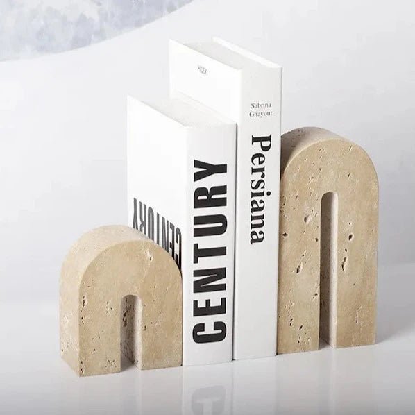 A set of two handcrafted, arch shaped travertine book ends holding white books