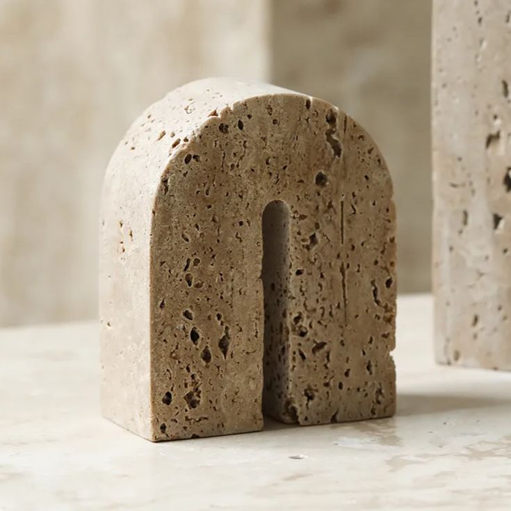 Handcrafted, arch shaped travertine book end on neutral background