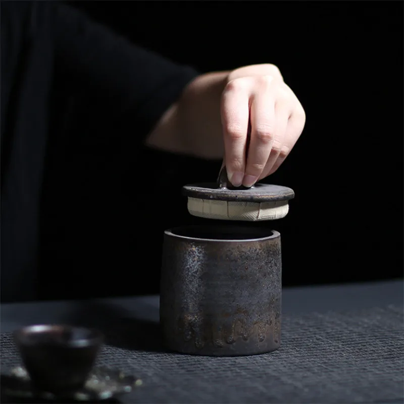 Hand opening dark grey ceramic storage jar with bronze accents 