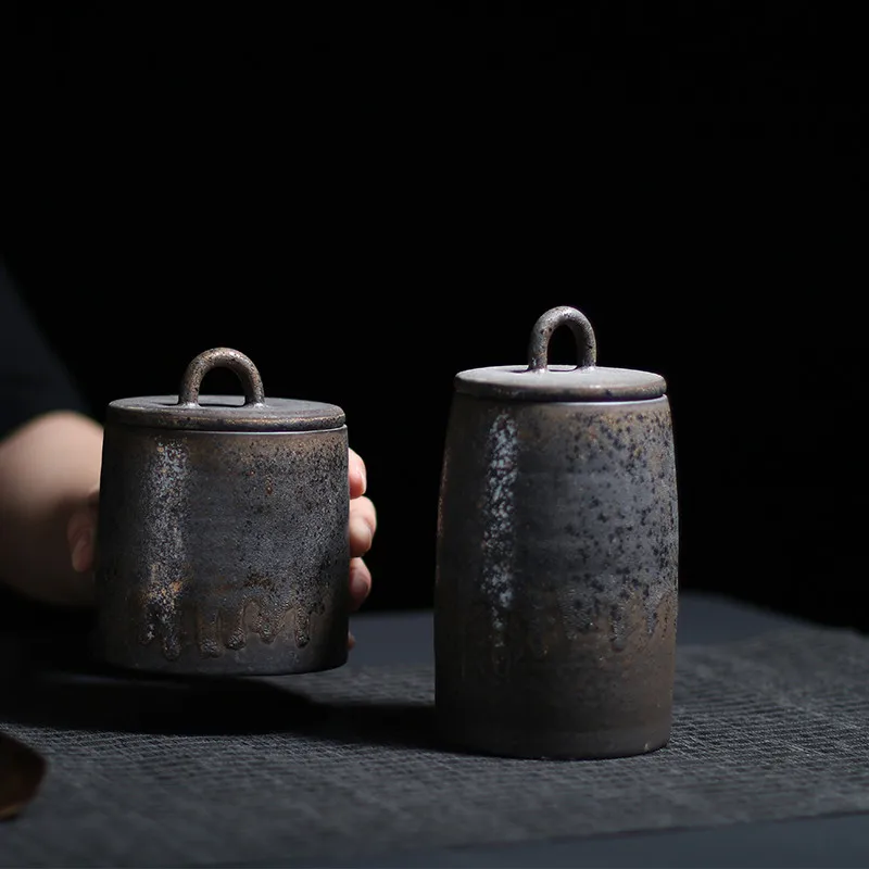 Set of dark grey ceramic storage jar with bronze accents on dark neutral background
