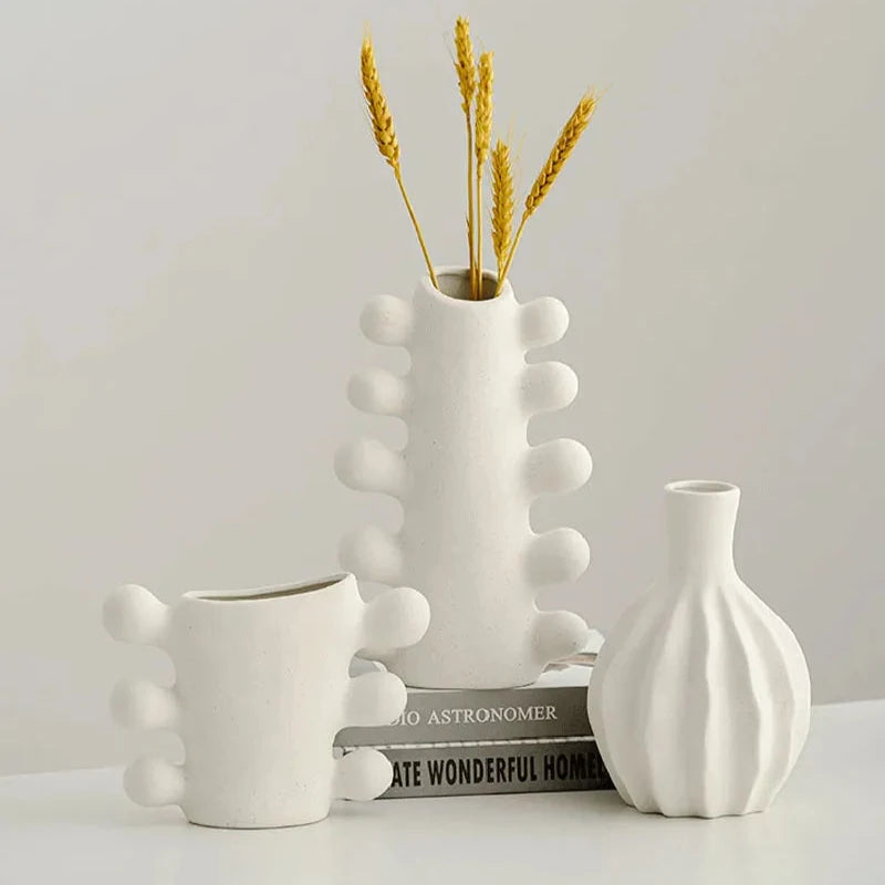 Set of three white textured vases with bubble design details on sides, with books on white background