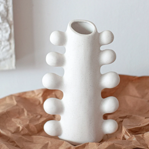 White textured vase with bubble design details on sides, on brown paper