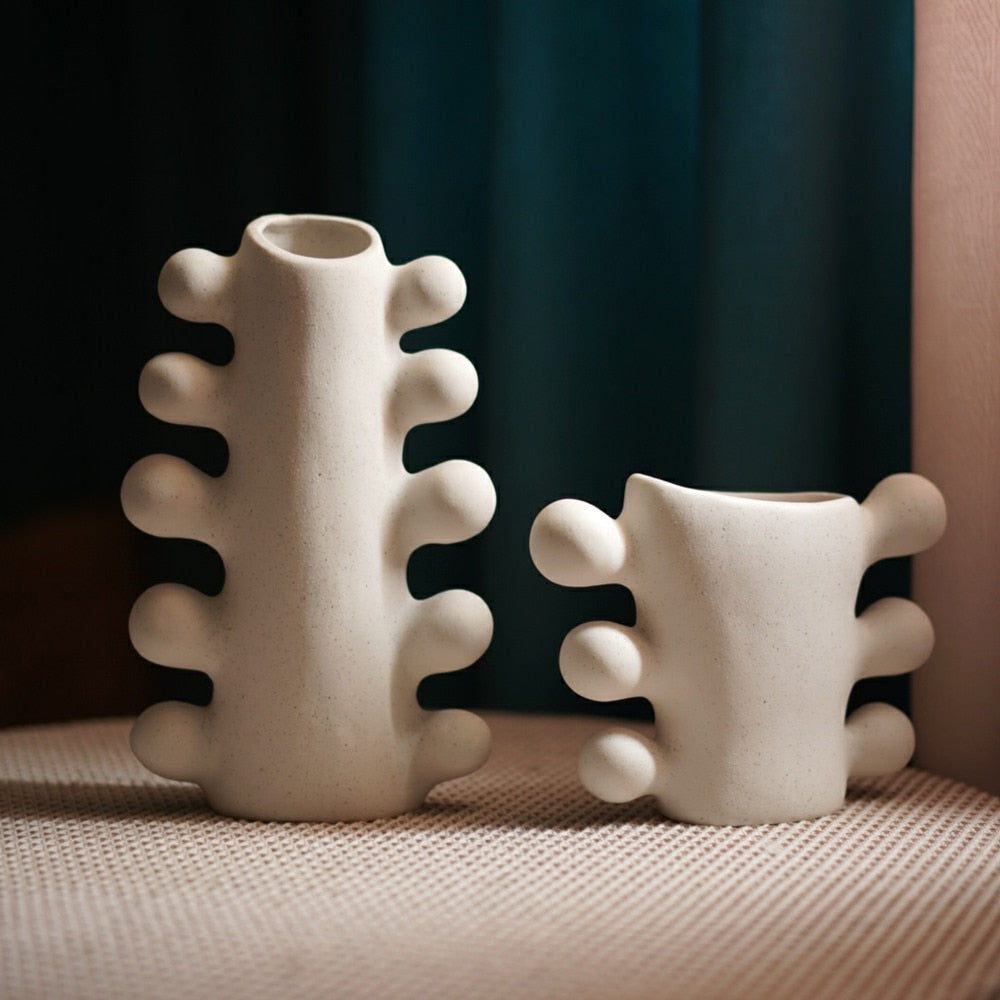 Set of two white textured vases with bubble design details on sides, with dark curtain background