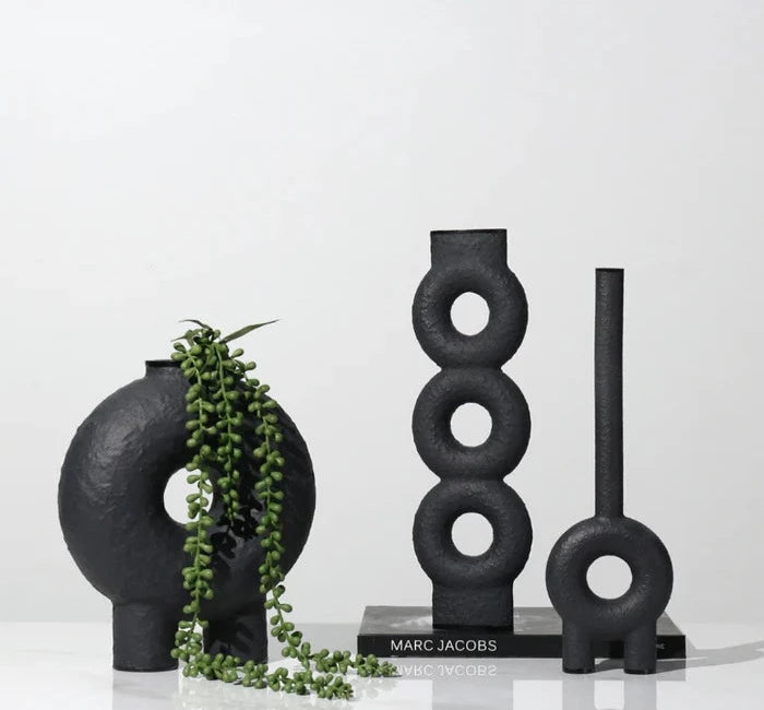 Set of three black  textured vases with circle design details on white background

