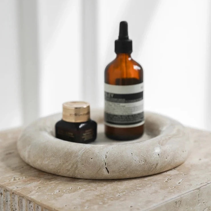 Round marble tray with skincare products in neutral room