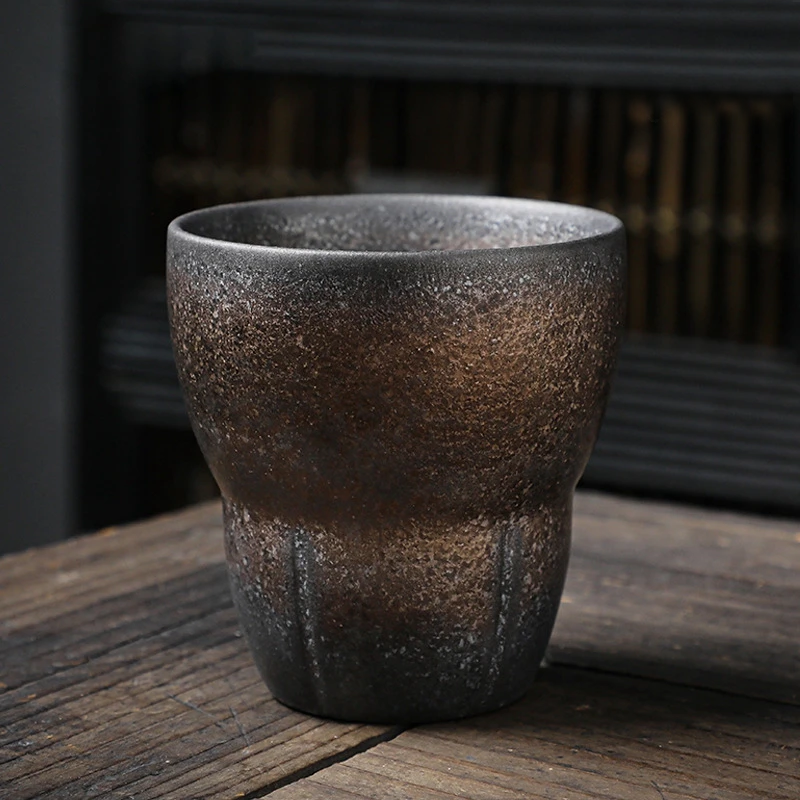 Grey ceramic drinking cup with bronze accents on wooden table