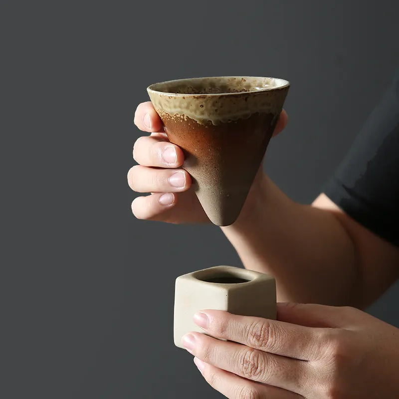 Woman holding conic cup and square ceramic base on dark background