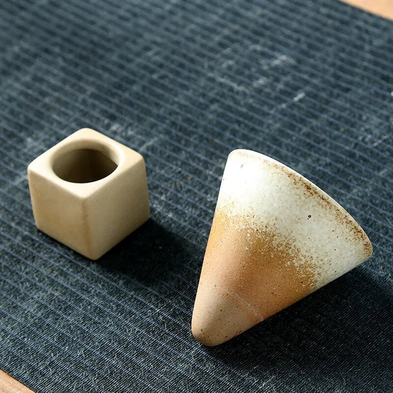 Beige conic cup and square ceramic base on dark tablecloth