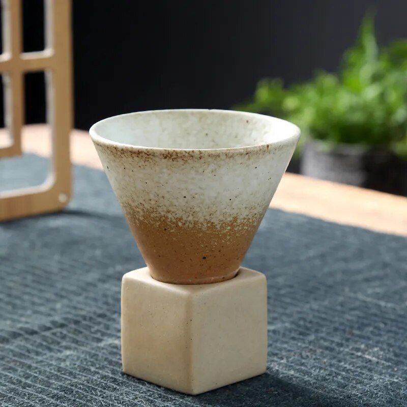 Beige conic cup and square ceramic base on dark background