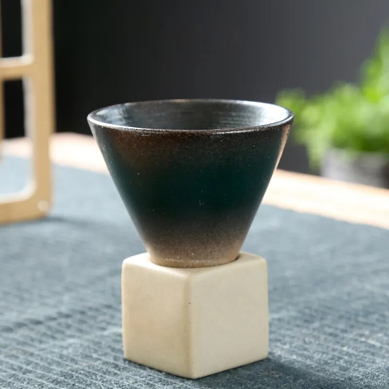 Black conic cup and square ceramic base on dark background