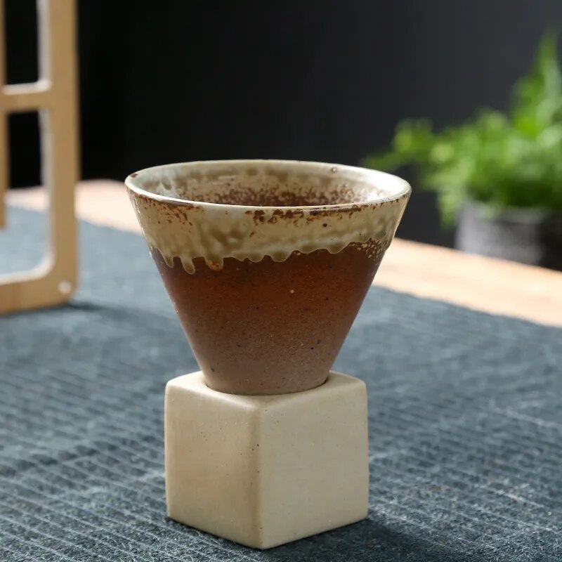 Brown conic cup and square ceramic base on dark background