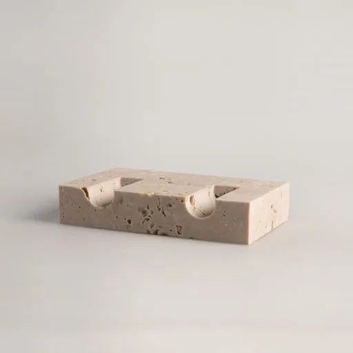 Detail of rectangular travertine candlestick holder on light neutral background