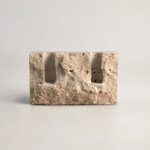 Rectangular travertine candlestick holder with rough finish on light neutral background