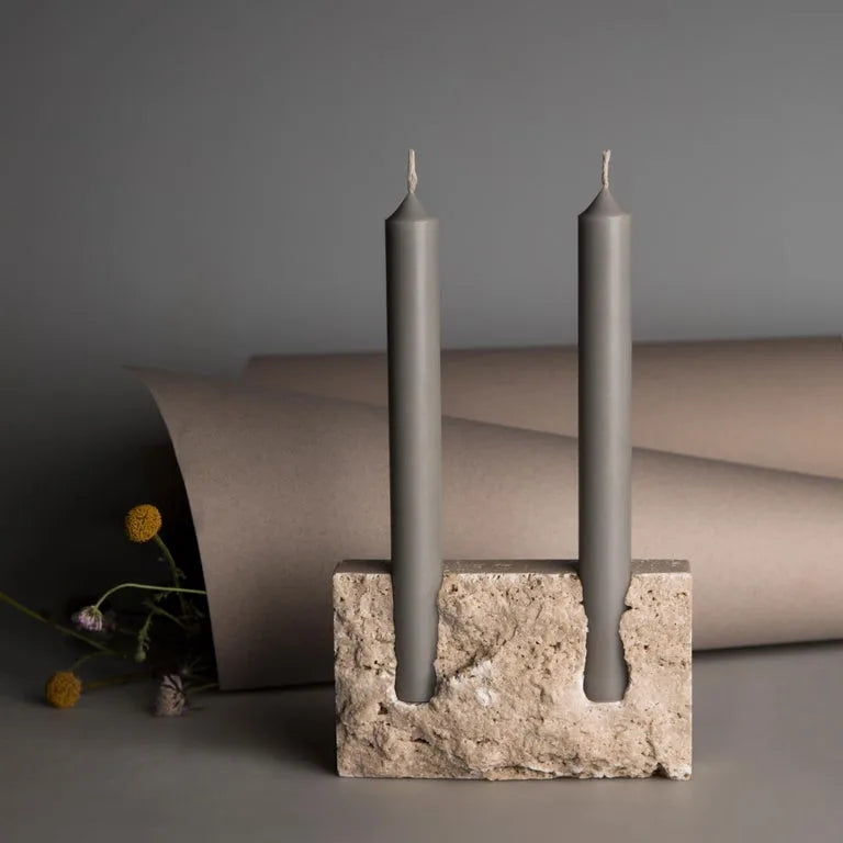 Rectangular travertine candlestick holder with grey candles on dark neutral background