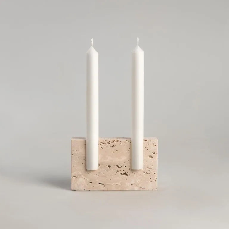 Rectangular travertine candlestick holder with white candles on light neutral background