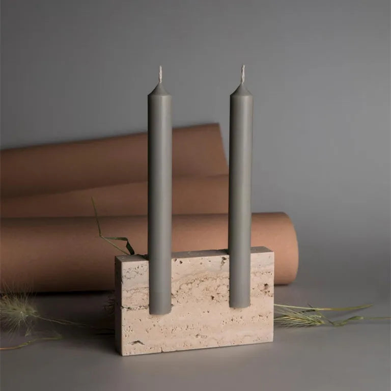 Rectangular travertine candlestick holder with grey candles on dark neutral background