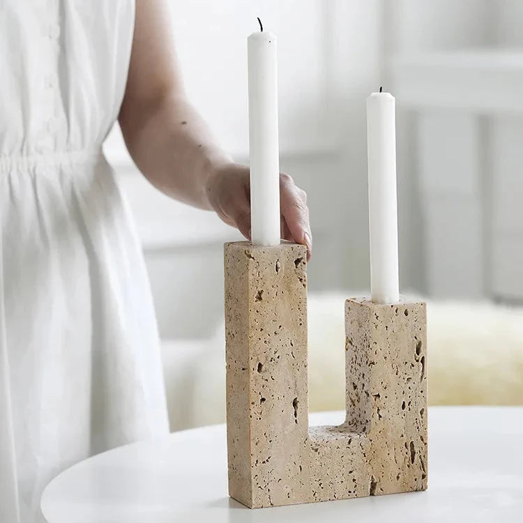 Woman’s hands with handcrafted travertine candle holder in bright room