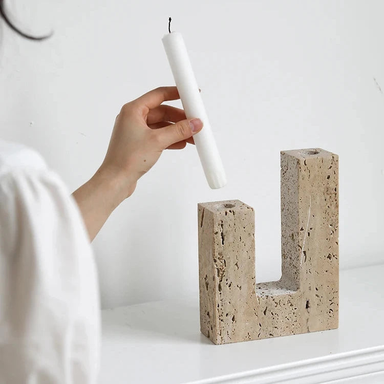 Woman inserting white candle in handcrafted travertine candle holder