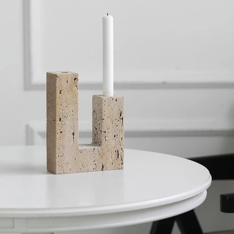 Handcrafted travertine candle holder with one white candle on table, in bright room