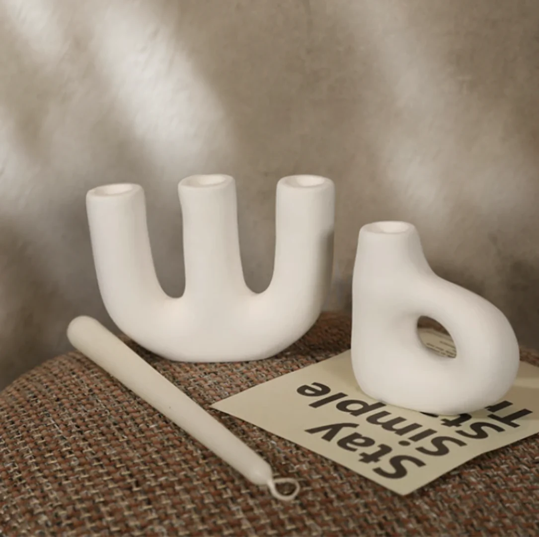 Set of two white organic shaped ceramic candle holders on neutral background