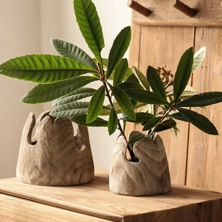 Set of two handcrafted japandi wooden vases with green leaves on wood bench