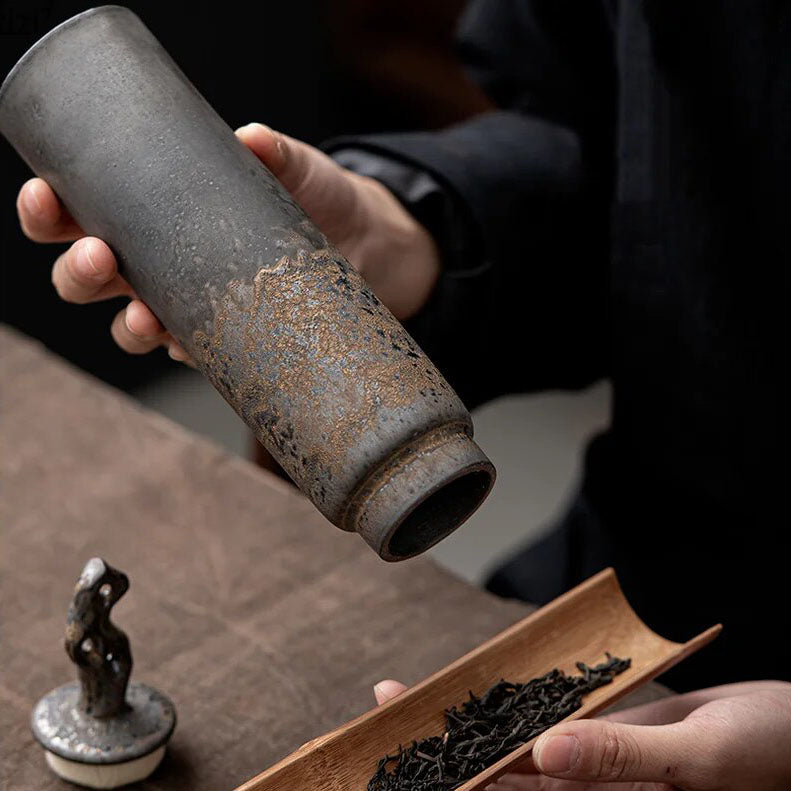 Hand pouring spices from dark grey ceramic storage jar with bronze accents