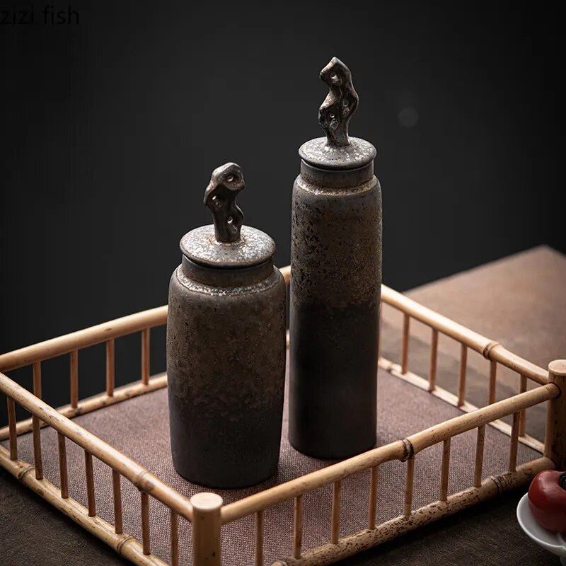 Set of two tall, dark grey ceramic storage jars with bronze accents on japanese tray and dark neutral background