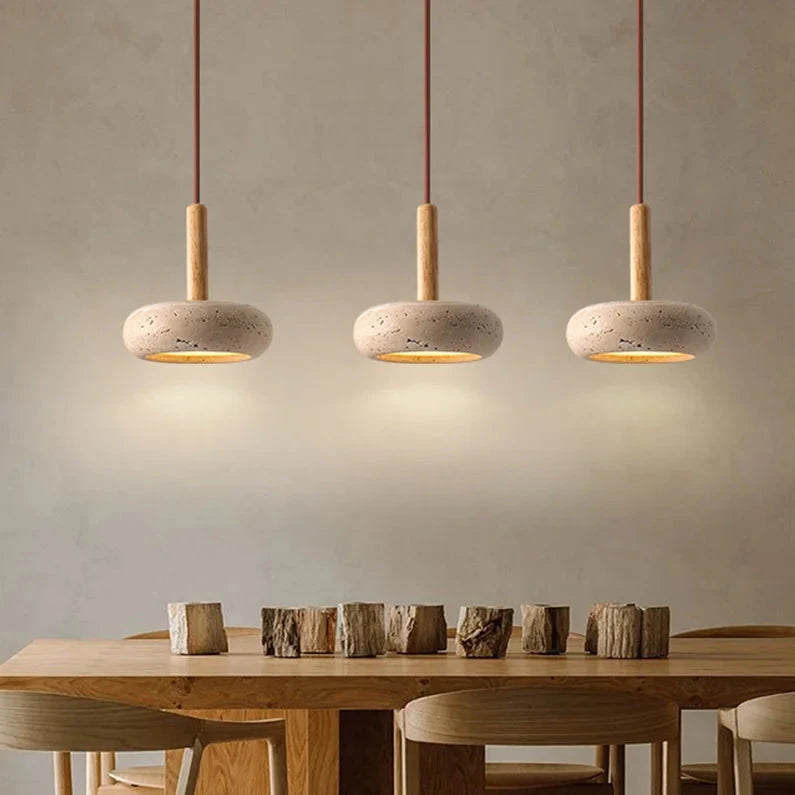 Three travertine japandi pendant lights hanging over wooden table