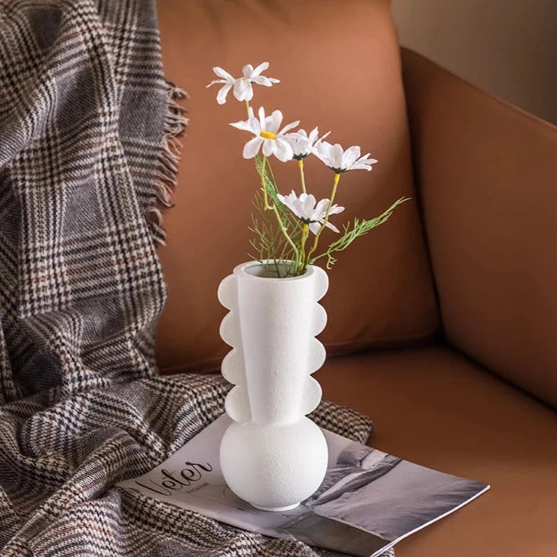 White textured vase with scalloped details on neck, on brown couch