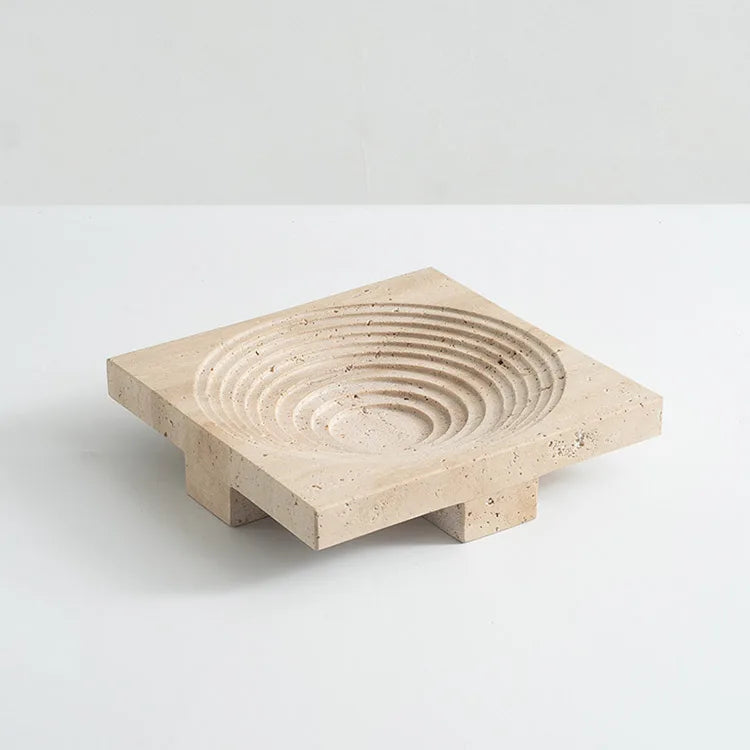 Square travertine round tray with concentric decoration and elevated base, on neutral background