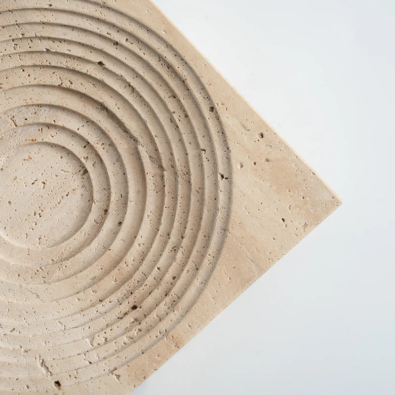 Detail of square travertine round tray with concentric decoration on neutral background