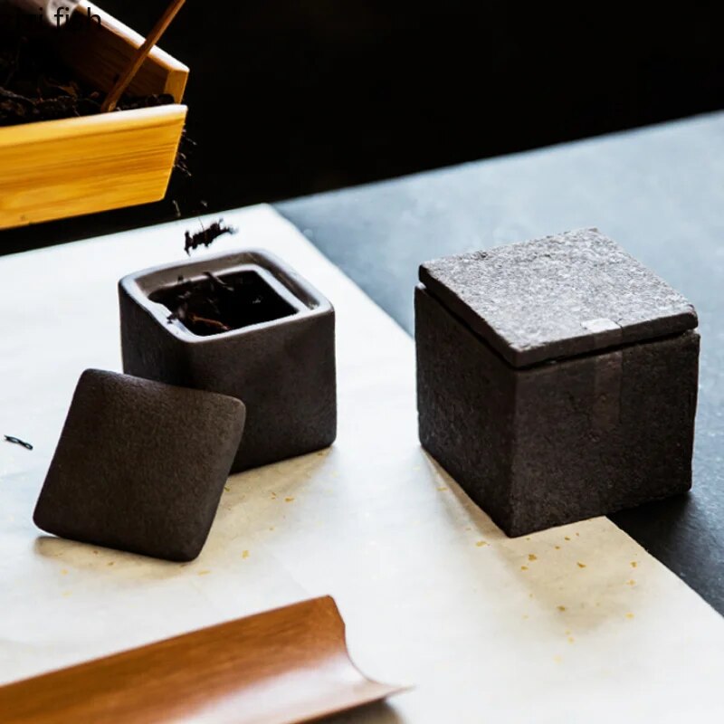 Set of two japandi dark grey textured square ceramic jars with decorative accent on dark neutral background