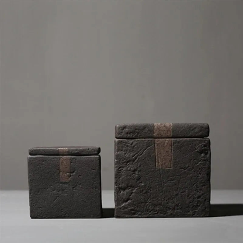 Set of two japandi dark grey textured square ceramic jars with decorative accent on dark neutral background