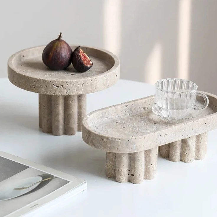 Two travertine trays with scalloped stands in neutral room