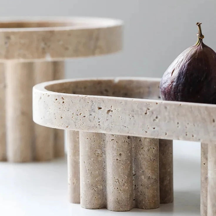 Details of two travertine trays with scalloped stands in neutral room