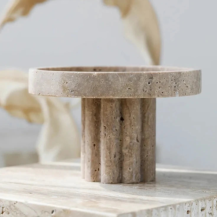 Side view of round travertine tray with scalloped stand detail in neutral room