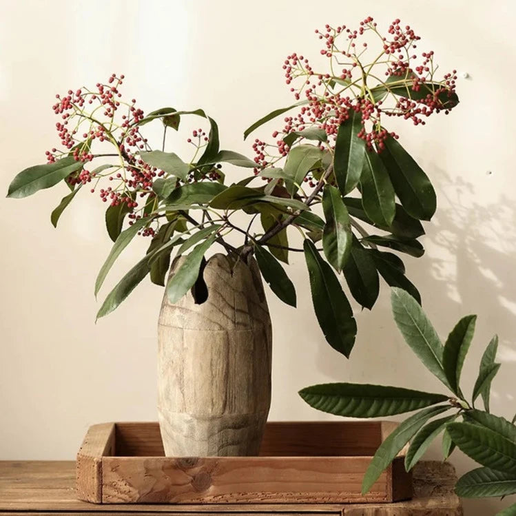 Tall, handcrafted japandi wooden vases with green leaves on wood bench