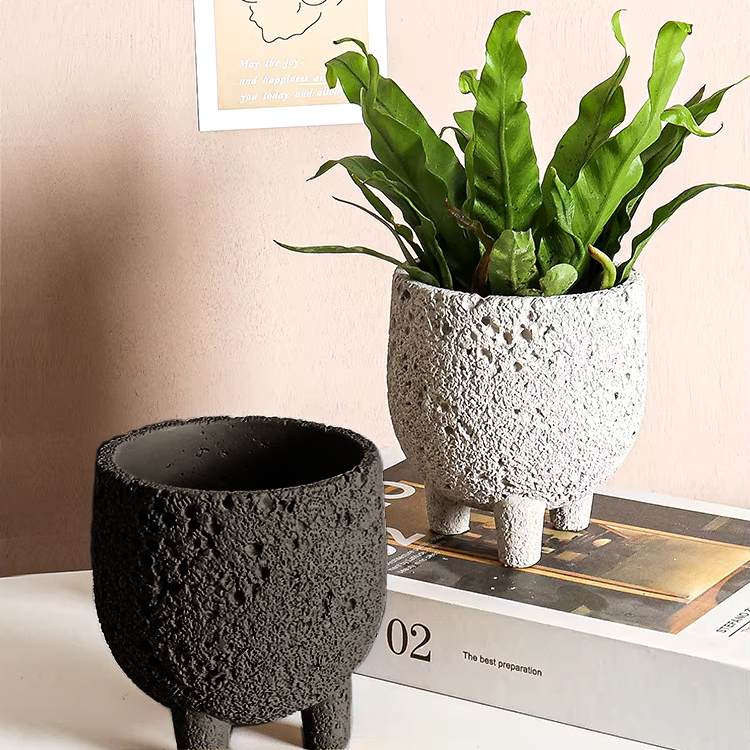 Set of two textured planters with feet, in neutral room with books