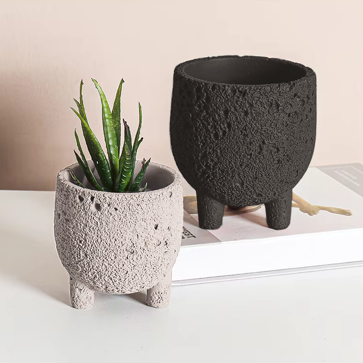 Set of two textured planters with feet, in neutral room with books